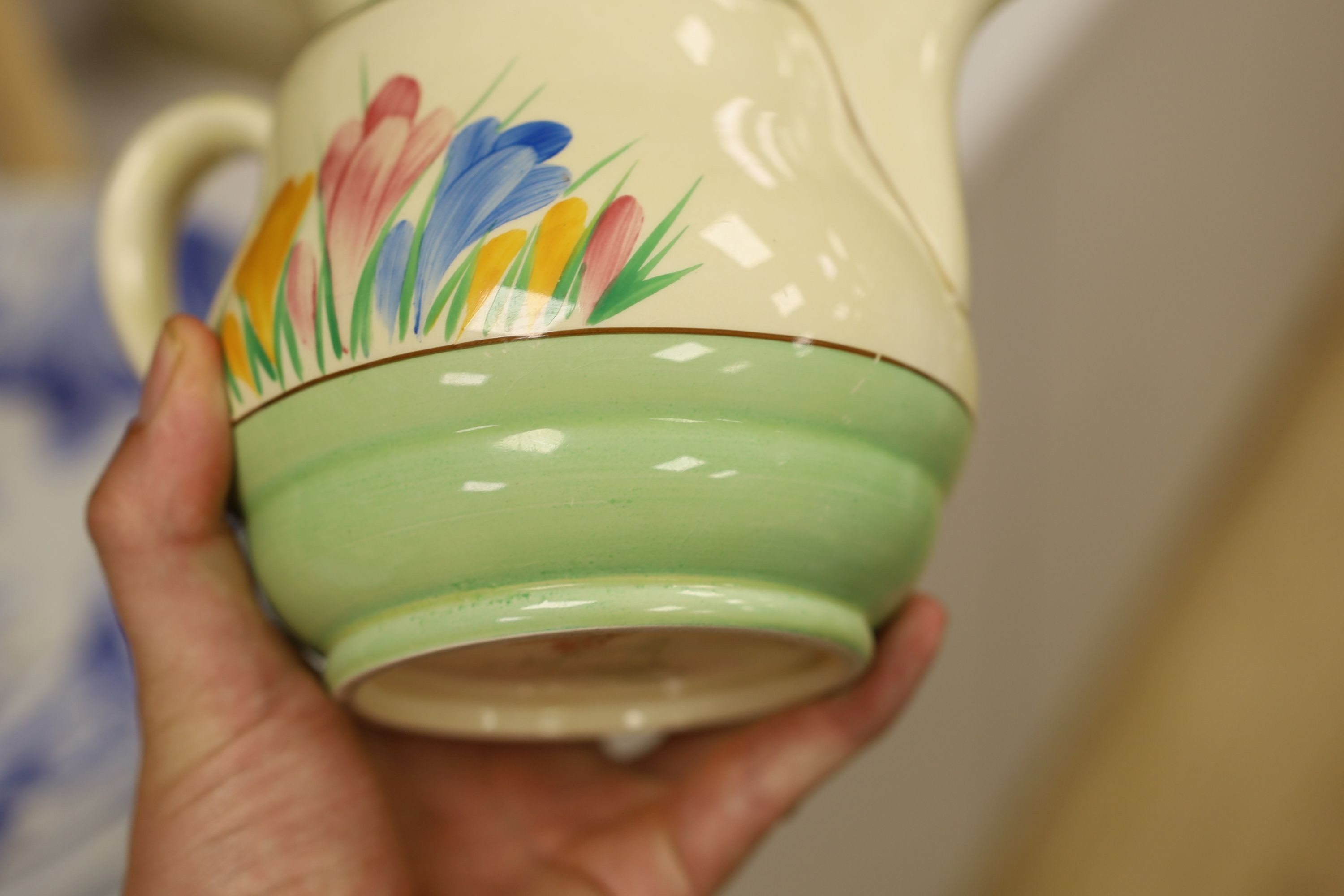 A Clarice Cliff crocus design milk jug and a Bizarre patterned side plate, jug 11.5 cms high